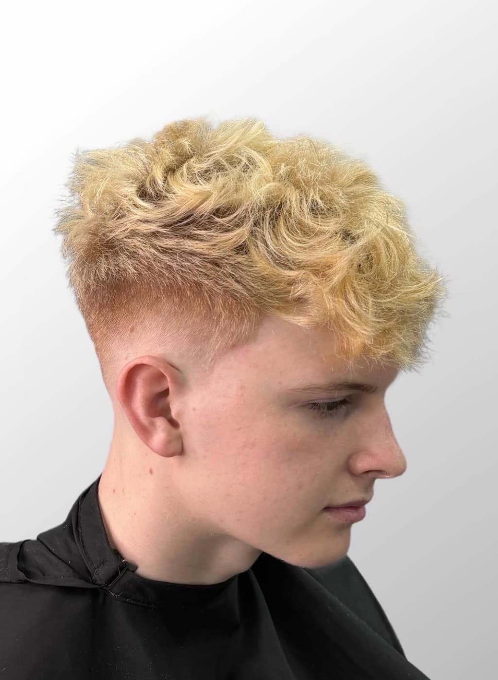 Bleached blonde curly crop over a high skin fade